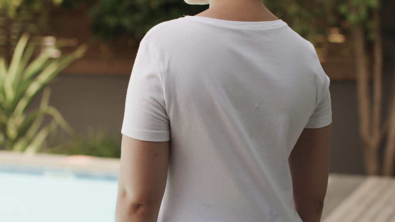 sección media de una mujer biracial vistiendo una camiseta blanca con espacio de copia en el jardín