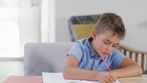 niño caucásico feliz sentado en la mesa y haciendo la tarea, espacio de copia, cámara lenta