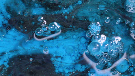 Abstract-art-background-of-swirling-blue-and-black-paint-with-bubbles-reacting-and-swirling