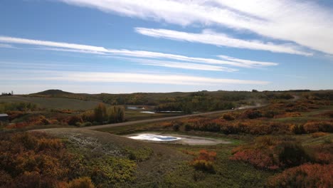 4k-drone-approaching-SUV-driving-along-dusty-dirt-road-during-a-sunny-autumn-day-in-the-countryside-of-Alberta,-Canada