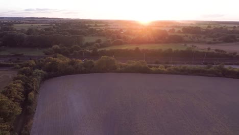 Volando-A-Través-De-Hermosos-Campos-Ondulantes-Lejos-De-Una-Impresionante-Puesta-De-Sol-Naranja