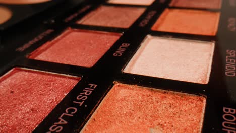 close-up of an eyeshadow palette with various shades of red, brown, and pink.