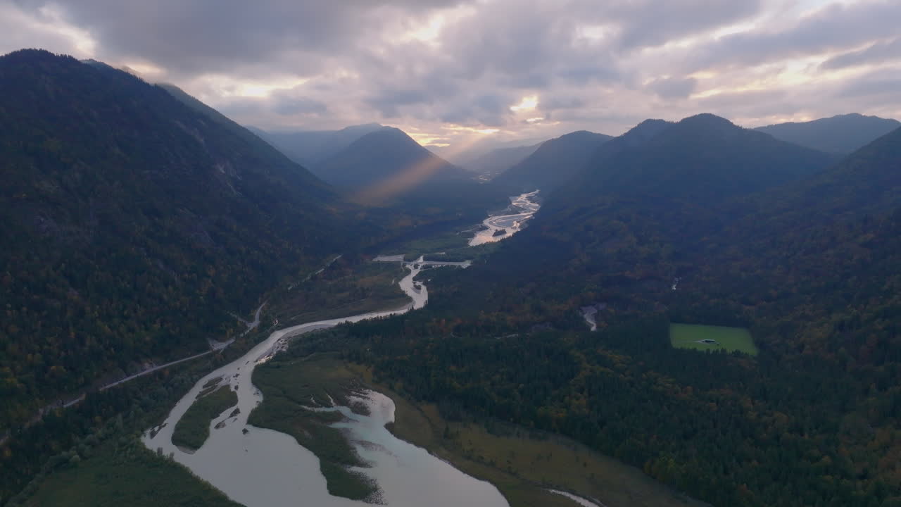 los rayos del sol brillan a través de la vista aérea de las montañas boscosas nebulosas sobre el sinuoso lago sylvenstein