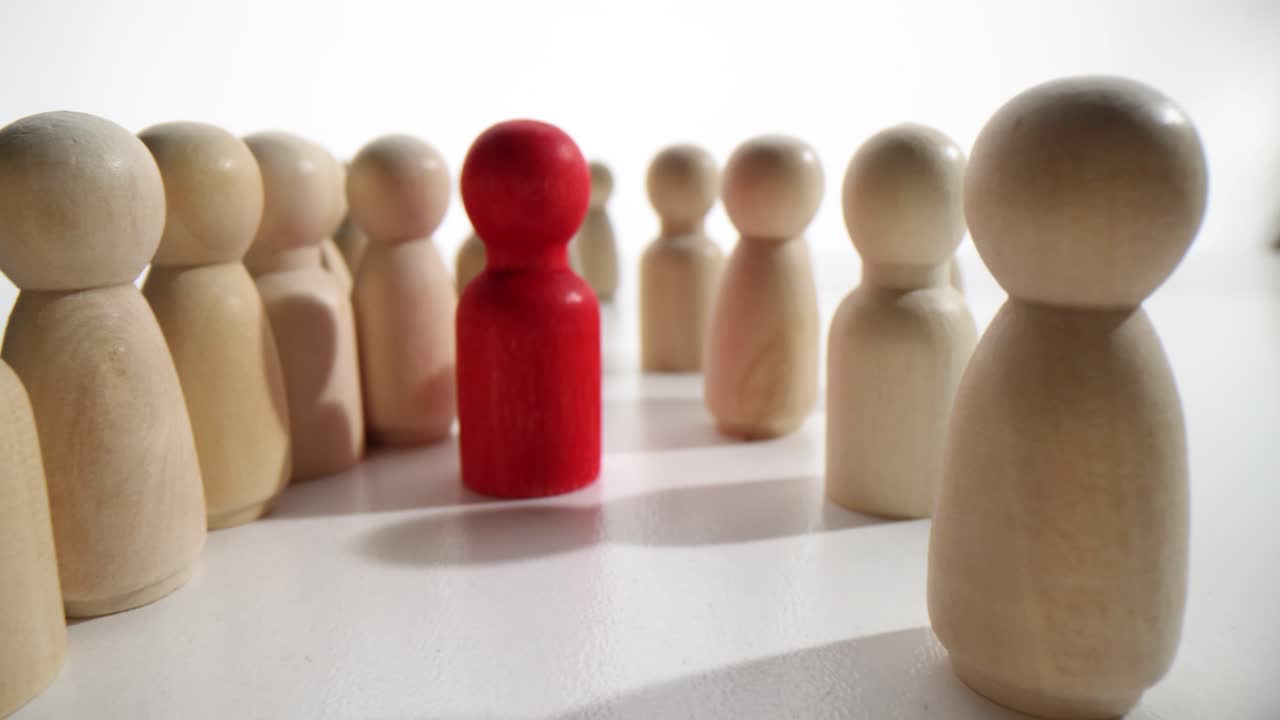 Red figurine stands between long rows of light figures