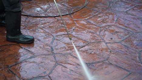 Extreme-closeup-in-slow-motion-of-a-person-power-washing-the-paved-sidewalk-in-a-park