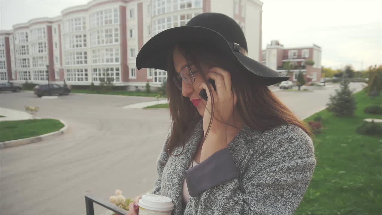 Young woman talking on phone outdoors, enjoying coffee