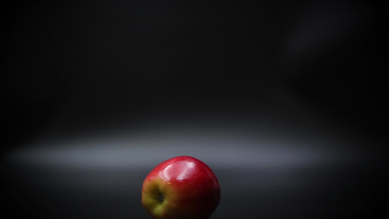 крупный план спелого красного яблока, крутящегося на черной поверхности, замедленная съемка
