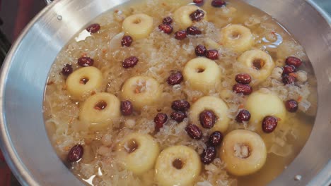 close-up shot of a traditional taiwanese sweet soup simmering in a pot, featuring whole pears, red dates, and snow fungus in a gently boiling, aromatic herbal broth