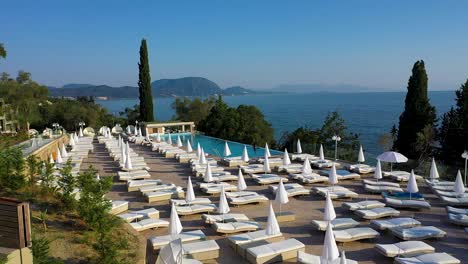 tracking shot hotel terrace with pool and sun beds. see the greek coast and the sea too.