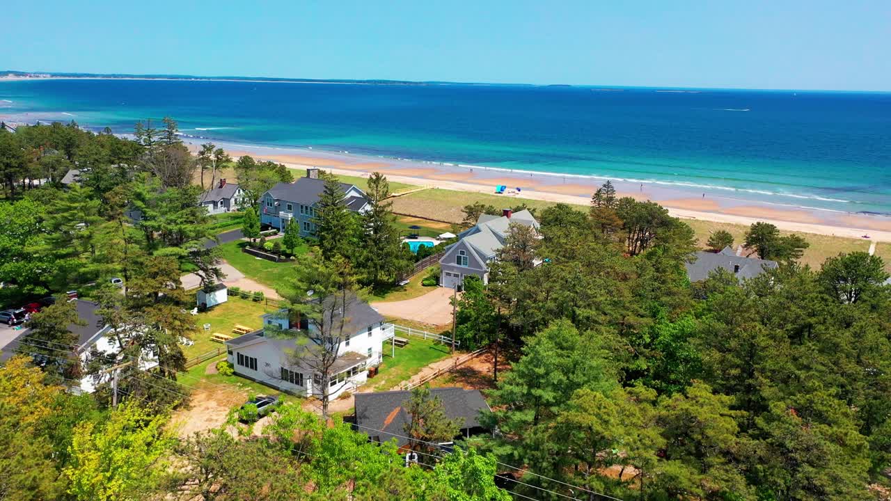 Drone shot of a Maine cottage with ocean views. Beach house features yard, patio, deck, and large windows overlooking the Atlantic. Relaxing waterfront real estate for vacation or living.