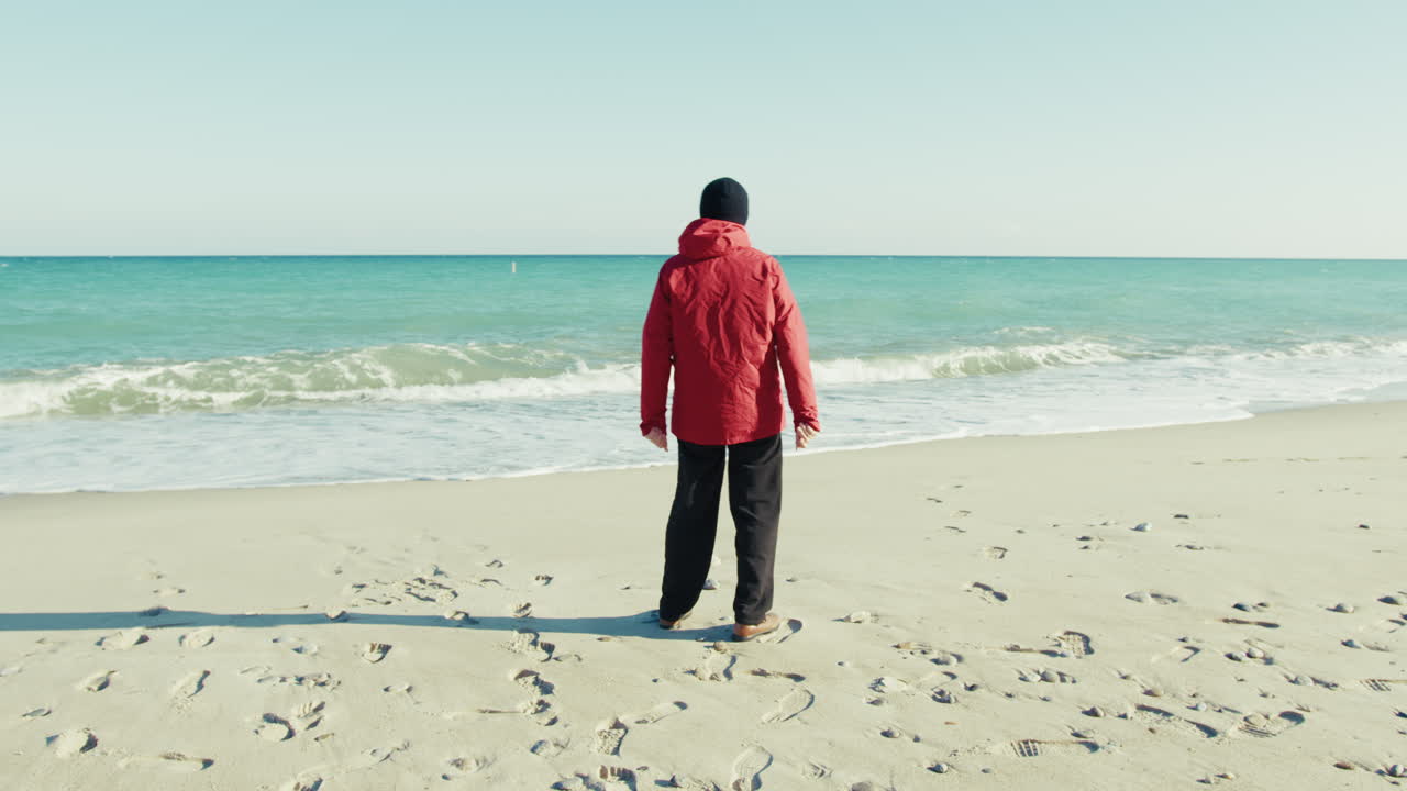 Elderly Man Picks Up Stones on the Sand and Throws Them into the Sea