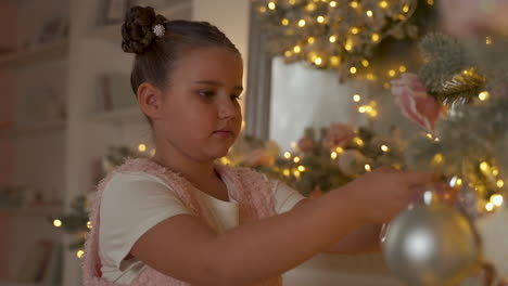 little girl decorating christmas tree with balls and ornaments