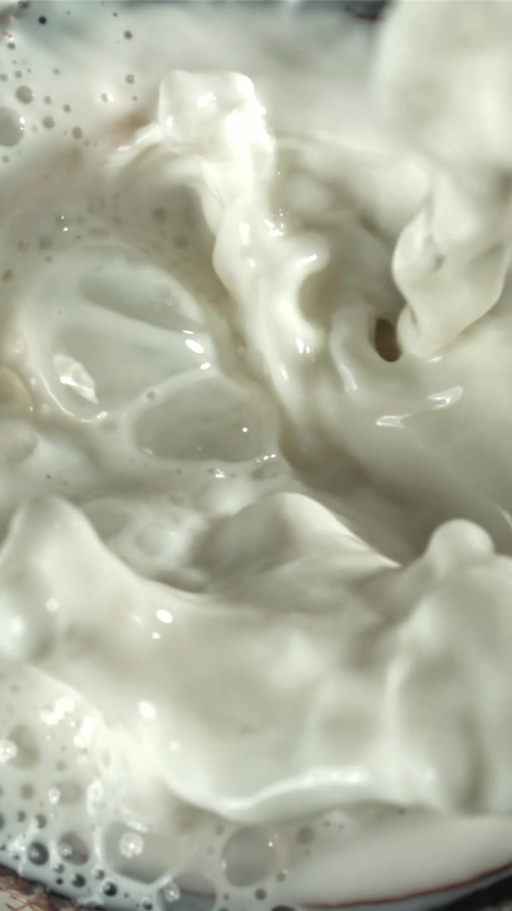 Vertido en cámara lenta de leche blanca creando salpicaduras y burbujas