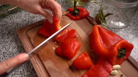 hands chopping roasted red bell pepper on wooden board