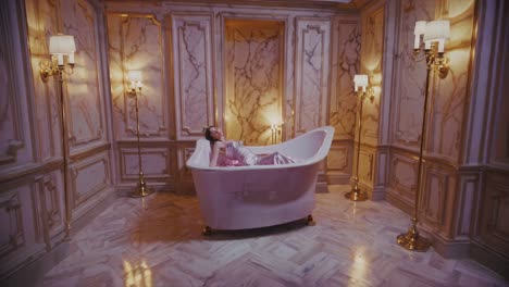 woman in a pink satin dress in a luxurious bathtub filled with rose petals