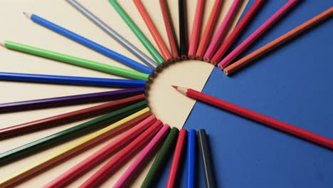 Close-up-of-crayons-arranged-on-beige-and-blue-background,-in-slow-motion