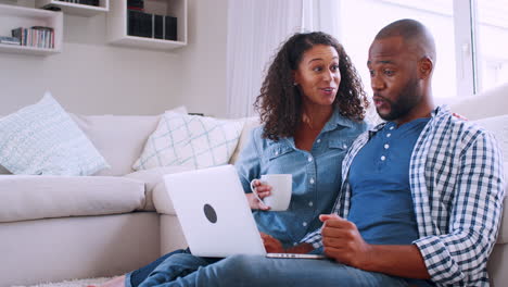 Young-black-couple-sitting-on-sofa-and-looking-at-computer