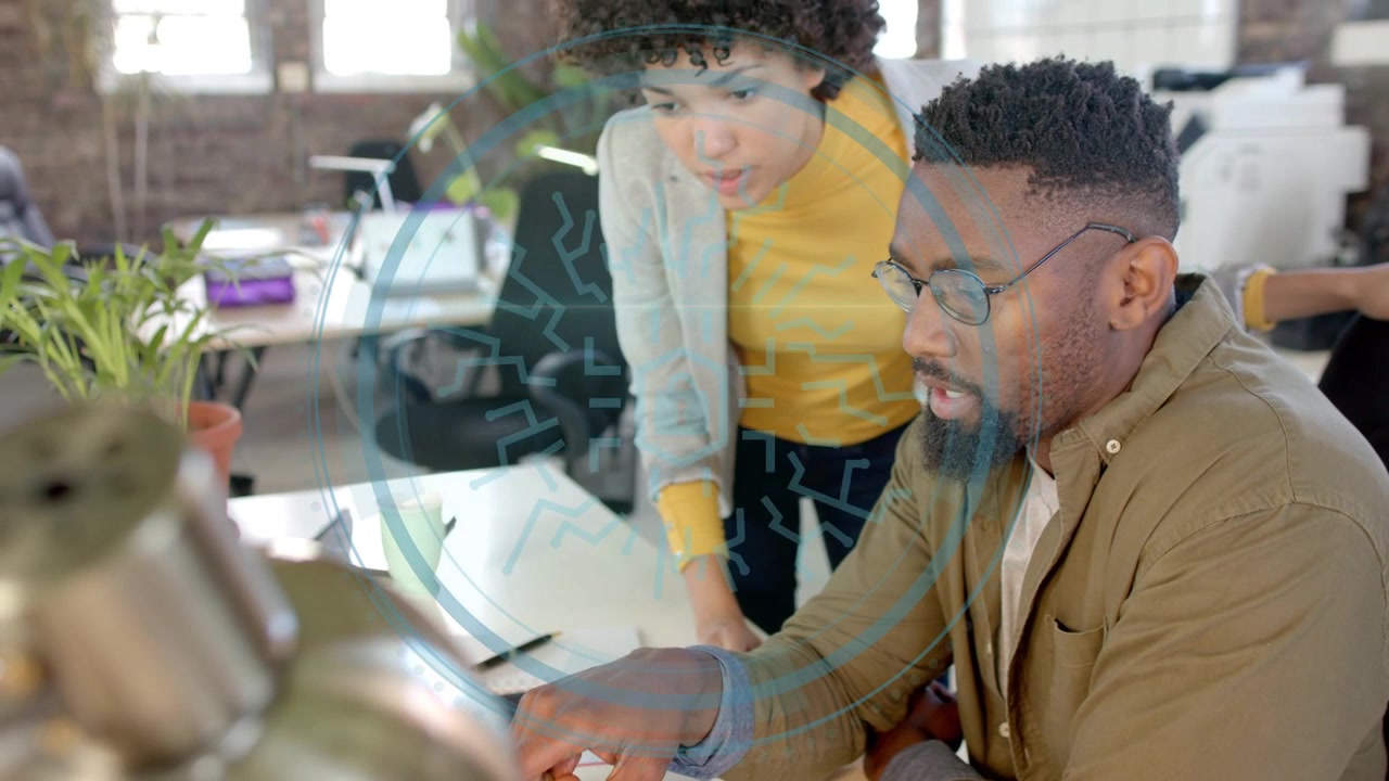 Female worker leaning in pointing at laptop, male worker typing HUD overlay expanding for business