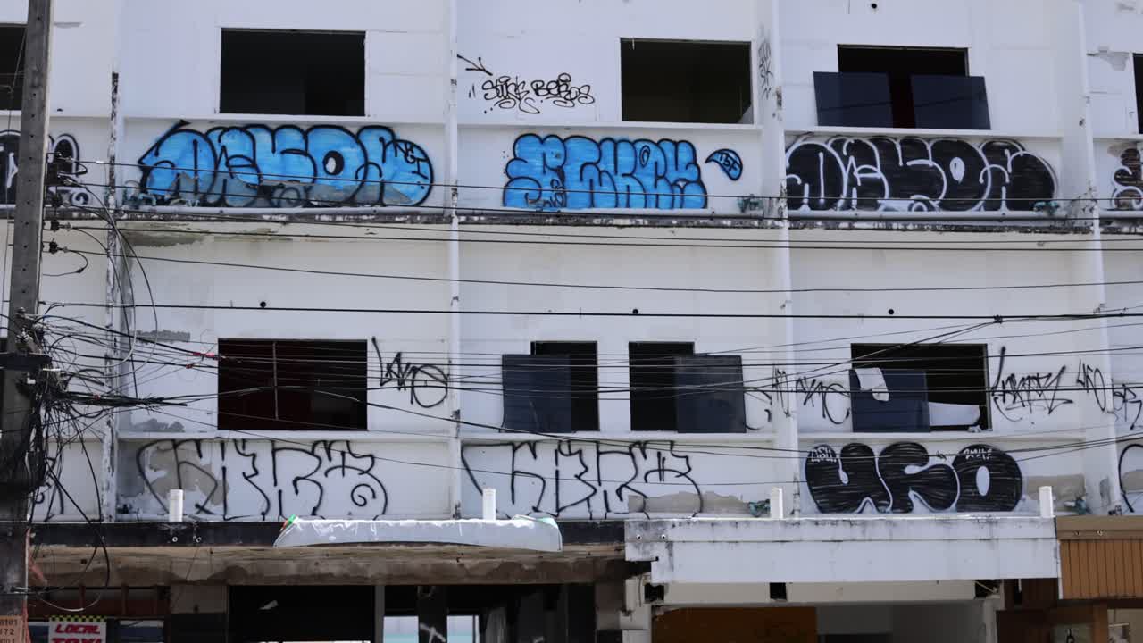 Graffiti-covered, abandoned building exterior with electrical wires.