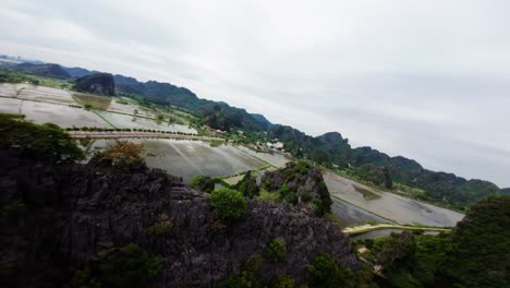 Drohne-Erhebt-Sich-über-Felsige-Klippen-Von-Tamcoc,-Vietnam,-Um-überschwemmte-Ländliche-Felder-Freizulegen