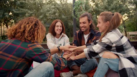 a company of two girls and two boys, sitting on bean bag chairs, folded their palms. rest in the country house