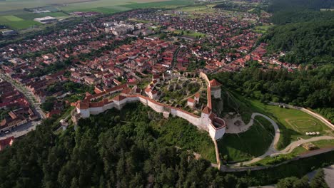 Rasnov-citadel-in-romania-with-town-and-green-landscape-in-daylight,-aerial-view