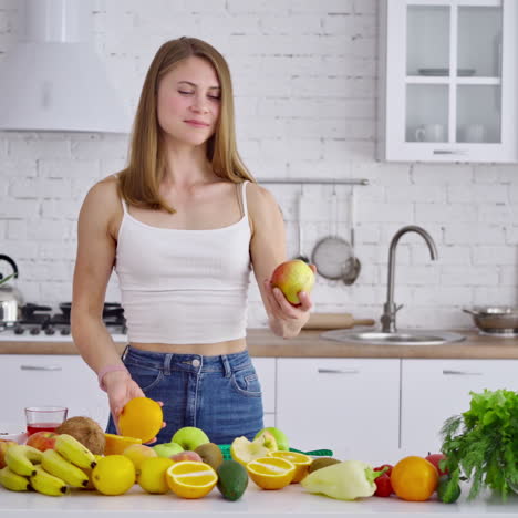 Portrait of beautiful girl in the kitchen. Vegetarian woman holding organic fruit. Happy young housewife near the table with fresh fruit and vegetables.