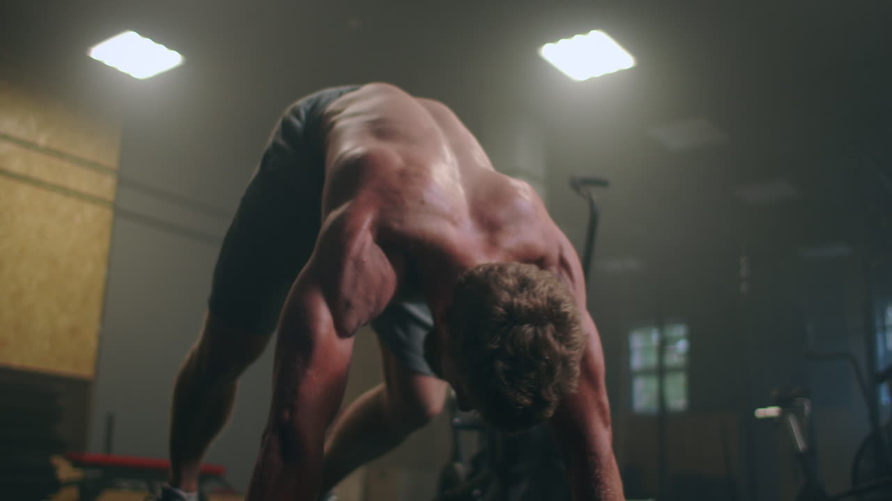 un hombre fuerte realiza flexiones desde el suelo con toda su fuerza. un hombre inflado hace flexiones en el gimnasio
