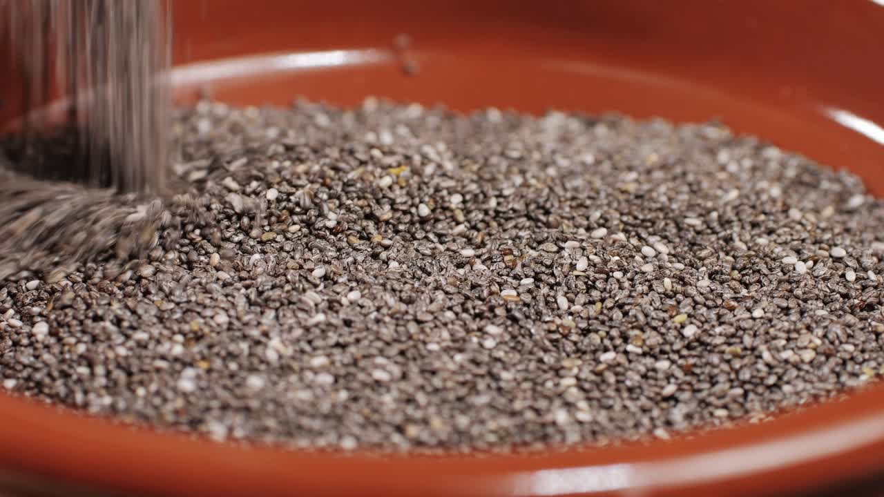 Chia seeds falling down on a plate close-up macro. Dry healthy ingredient. Healthy superfood rich in Omega 3 fatty acids. Salvia hispanica