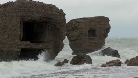 Grandes-Olas-Tormentosas-Rompiendo-Contra-Las-Ruinas-Abandonadas-Del-Edificio-De-Fortificación-Junto-Al-Mar-En-Los-Fuertes-Del-Norte-De-Karosta-En-Liepaja,-Costa-Del-Mar-Báltico,-Salpicadura-De-Olas,-Día-Nublado,-Plano-Medio