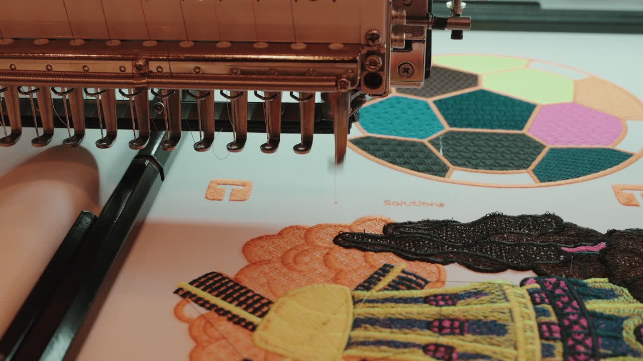 close up of embroidery machine stitching vibrant multicolor pattern on white fabric surface