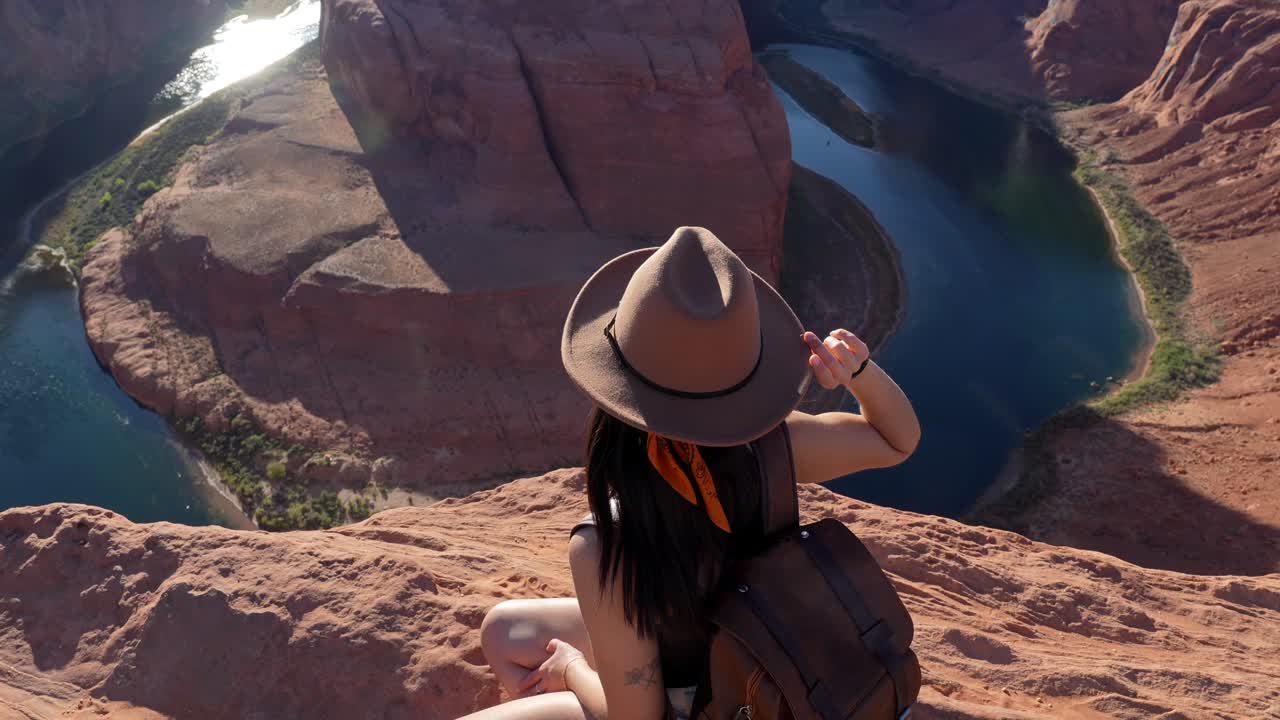 Giovane donna seduta sul bordo di una scogliera con vista su Horseshoe Bend