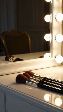 makeup brushes on vanity table with mirror and lighting