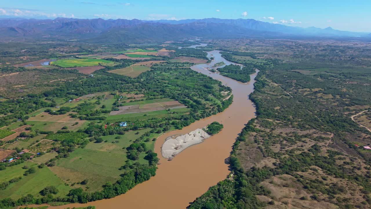 A unique aerial reveals vibrant green land contrasted by a winding brown river beneath a deep blue sky. A cinematic, Amazon-like scene capturing the raw beauty and harmony of nature