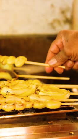 vendedor parrilla pinzas de calamar en el mercado flotante
