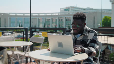 hombre trabajando en una computadora portátil en un café al aire libre