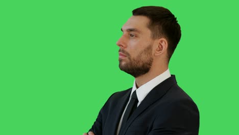 mid closeup shot of a profile of businessman in a tailored suit crossing arms on his chest and smiling warmly. shot on a green screen background.