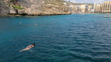 Mujer-En-Bikini-Negro-Bucea,-Nada-En-La-Playa-Malta-Xlendi-Azul-Profundo