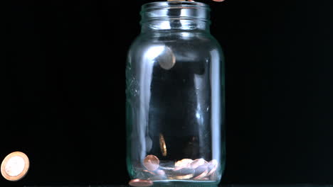 many coins pouring into glass jar