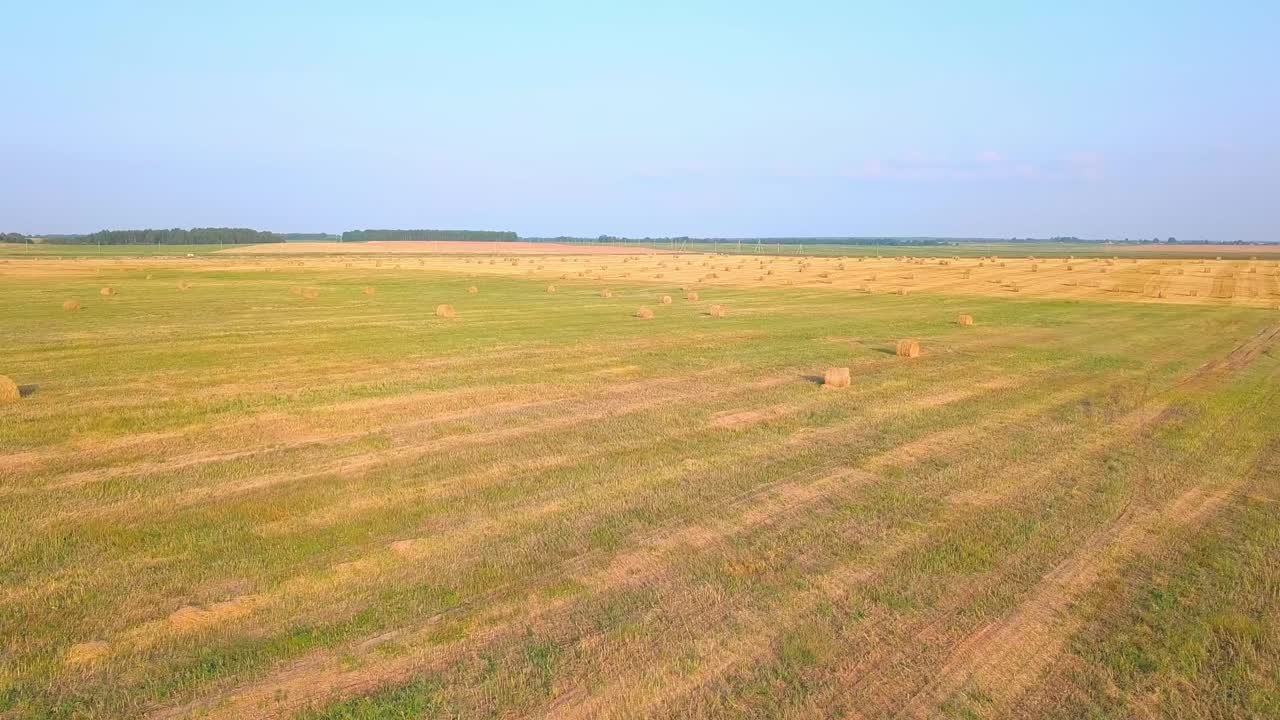 дрон летит над полем, где есть стопы сена с сена.