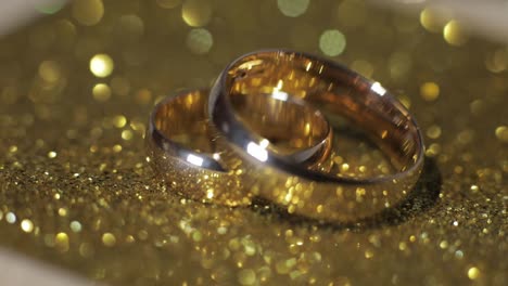 wedding gols rings lying on shiny glossy surface. shining with light. close-up