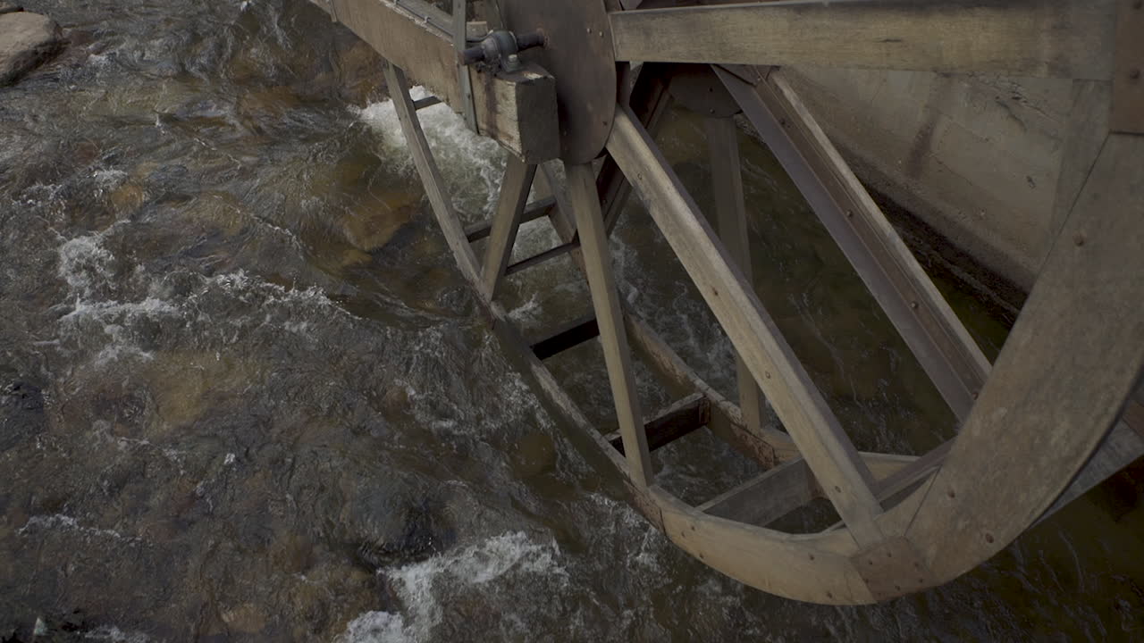 река течет под старым антикварным водяным колесом в горном городке в колорадо