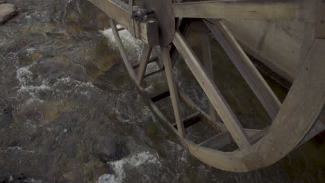 river flowing underneath an old antique water wheel in a mountain town in colorado