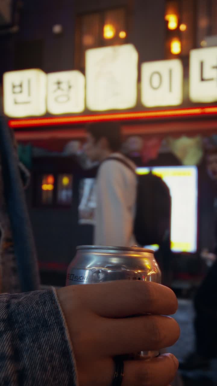 Young Person Drinking a Soda on a City Street at Night