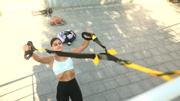 женщина занимается тренировкой на подвеске на открытом воздухе