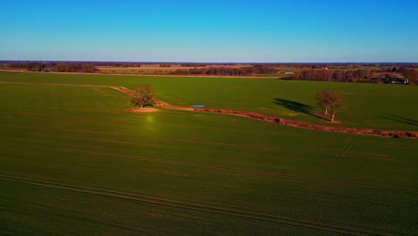 aerial drone forward moving shot over an empty waterway of irrigation system through green farmlands on a sunny day