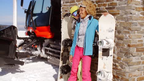 Close-couple-posing-with-snowboards-against-garage