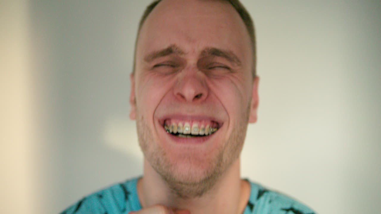 el joven se cubre la cara con ambas manos, luego las quita y se echa a reír