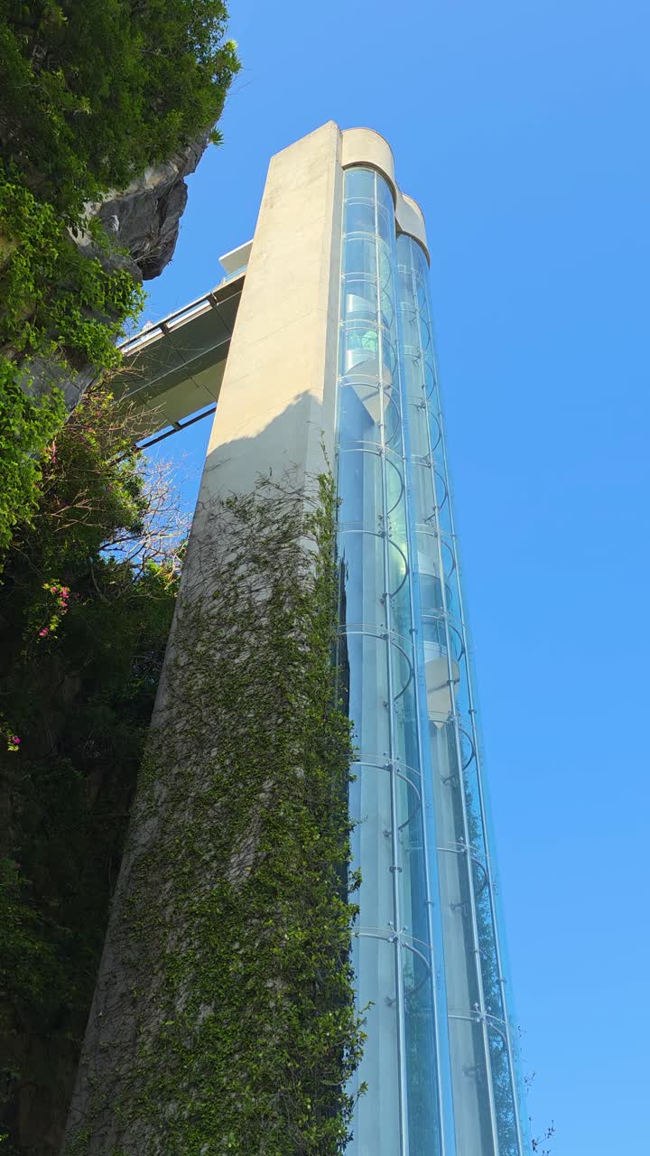 Toma vertical de un ascensor de cristal transparente subiendo a lo largo de la exuberante montaña de mármol de piedra caliza verde en Da Nang, Vietnam