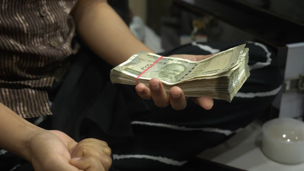 Closeup of a person comparing 24k raw gold and Indian rupee banknotes for gold investment